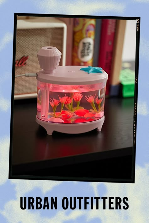 Add moisture to any space to help prevent dry skin with this itty bitty humidifier featuring an aquarium silhouette. Doubling as a nightlight, this humidifier is equipped with two mist modes and it’s super quiet so your sleep or work won’t be disturbed. Finished with a duo of faux fish and florals that you don’t have to remember to feed! Features Mini humidifier Aquarium design Color-changing light Ultra-quiet so your routines aren’t disturbed 2 Mist modes: continuous & interval Petite size fits anywhere Content + Care Silicone, metal, acrylonitrile butadiene styrene, polycarbonate silicone, metal, acrylonitrile butadiene styrene, polycarbonate Wipe clean Imported Size Dimensions: 5.7" l x 5" w x 3.4" h | Mini Aquarium Humidifier in Pink at Urban Outfitters Mini Aquarium, Aquarium Design, Color Changing Lights, Cute Room Decor, Tech Gifts, Fish Tank, Bedroom Makeover, Things To Buy, Room Inspo