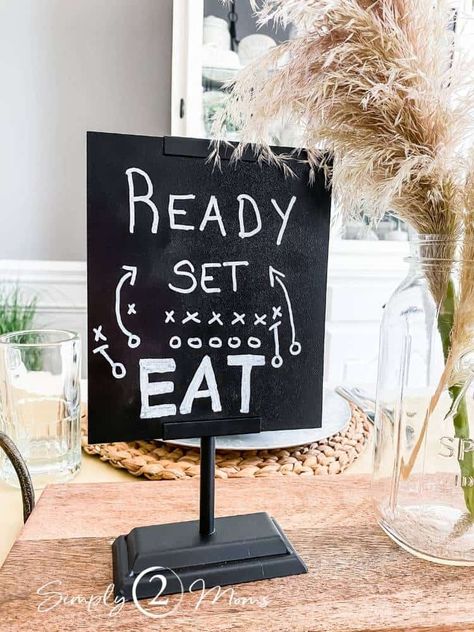 Are you ready for some football? You'll be ready to entertain with our 5 simple ideas for the best football tailgate party tablescape. Birthday party, football watching, or Super Bowl inspiration. Simple football themed centerpiece ideas using pampas grass, faux onion grass, diy flags, and chalkboard signs. Place settings with sea grass and galvanized metal chargers, ticking striped farmhouse napkins and chalkboard place cards. Easy fall party decorating ideas. NFL, college or any football game. Themed Centerpiece Ideas, Tailgate Party Ideas, Tailgate Party Decorations, Diy Flags, Football Centerpieces, Football Tailgate Party, Tailgate Decorations, Football First Birthday, Football Banquet