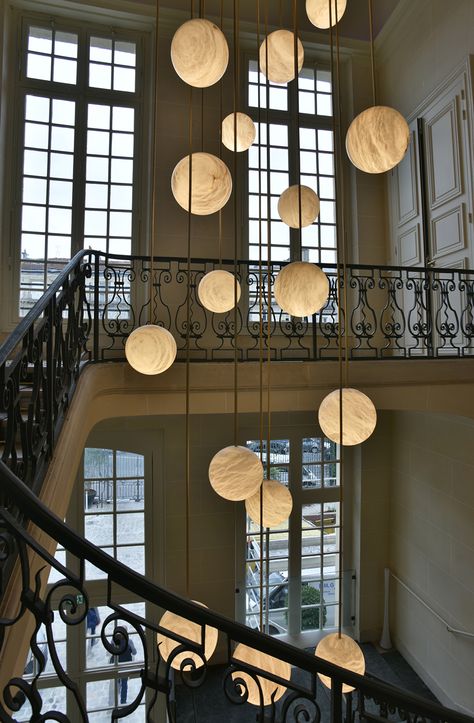 Look up and discover our majestic composition of LUNAs alabaster spheres! Escape for a poetic gateway in the heart of the Quartier Latin in Paris, and let you mesmerised by this mansion’s grandiose staircase, highlighted by our dreamy creations. Our imagination and know-how enable us to reinvent our most iconic alabaster sphere to realise your most wonderful dreams. Thank you, Cercle Lebrun, for your trust. Staircase Pendant Lights, Chandeliers For Staircase, Chandelier In Stairwell, Alabaster Furniture, Lighting Staircase, Lamp Staircase, High Ceiling Decorating, Chandelier Staircase, Student Accomodation