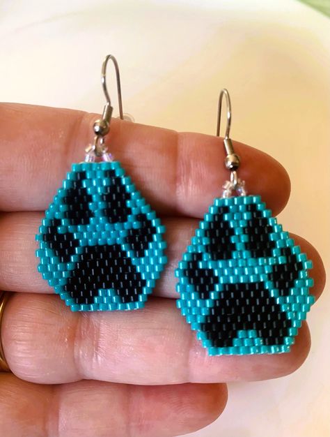 Hand beaded wolf paw earrings for those who love all things nature, native or wolf. The earrings are made with size 11 Miyuki glass beads which are uniform in shape and color and threaded together with fire line thread for durability and hung on a stainless-steel ear hook that is approved for sensitive skin.  The finished earrings pictured are turquoise, but I will make to order a color you prefer, just message me with your request.  Your earrings will arrive in box with a ribbon just in case yo Beaded Patterns Native, Bear Paw Beaded Earrings, Paw Print Beaded Earrings, Wolf Beading Patterns, Beaded Paw Print, Beaded Wolf Earrings, Brick Stitch Wolf Earrings, Rhinestone Patterns, Earrings Handmade Beaded