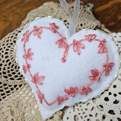 A very special beaded heart shaped felt ornament featuring a tiny hand stitched border design for a romantic, lovely keepsake. Each ornament may differ slightly but all will be the same unique design and quality as shown. This  ornament is individually handcrafted from heavy quality felt in neutral colors. They are embroidered with DMC embroidered floss. Beautiful elongated white glass beads embellish the blanket stitched edge.  It measures 4" x 4" at the widest and deepest part of the heart design. It has been lightly stuffed with a poly fill. I usually have these pre- made so they can be shipped within one day of order. At most, they'll will be shipped within 3 days. They do take approximately 1 1/2 hours each to make.  If you would like a different color combination, please contact me. Felt Hearts Diy, Felt Heart Ornaments, Felt Hearts Crafts, Memory Clothes, Felt Valentine, Pocket Hearts, Material Pictures, Coral Embroidery, Embroidery Felt