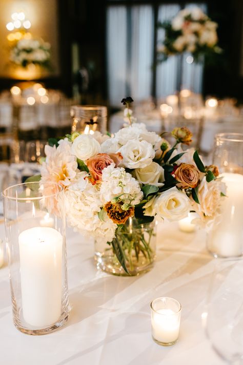 White, blush, and dusty pink wedding centerpiece. Pillar candles and votive candles surrounding low fall wedding centerpiece. PC: Emily Wren Photography https://emilywren.com/ Simple Wedding Table Centerpieces Votive Candles, Dusty Pink Centerpiece Wedding, Bud Vase Pillar Candle Centerpiece, Pillar Candles Wedding Centerpiece, Pillar Candles And Bud Vases Wedding, Pillar Candle Floral Centerpiece, Candle Centerpieces Wedding Round Table, Cylinder Vase Centerpiece Wedding, Candle Greenery Centerpiece