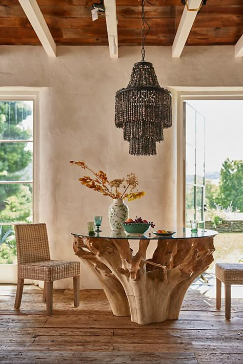 A statement piece to treasure for years to come, this teak root dining table is defined by its gorgeous hand-carved base and pristine glass top. A perfect balance between modern and rustic, natural and sleek, this table blends seamlessly into a range of decor styles. Material Note This product is made from teak root left in its raw form. Furniture makers cut and carve the pieces out of the naturally-tangled shape of the teak tree roots, so please expect variations in shape, color, and appearance. There may also be naturally occurring " imperfections," such as superficial cracks and blemishes. | Glass Top Teak Root Dining Table at Terrain Coastal Kitchen Table, Brown Furniture Decor, Rustic Wood Tables, Wood Glass Table, Earth Kitchen, Puerto Rico House, Anthropologie Decor, Kitchen Booth, Surf Bar