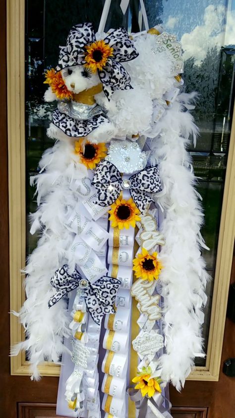 Luxury senior triple homecoming mum in white, silver, and gold.  Accented with sunflowers and a plush teddy bear and leopard print bows.  Custom layered lettering and feathered boa. #hoco2019 #hoco2k19 #hoco19 #homecomingmum #classytouchdesigns #homecoming2019 #rattlerfootball #navasotarattlers #rattlernation #asowls #ASCISD #andersonshirohighschool #andersonshiro #andersonshiroowls #homecomingmums #luxuryhomecomingmum #fancyhomecomingmum Senior Mums Homecoming White And Silver, Mum Inspiration, How To Make Mums, Hoco Mums, Senior Mums, Homecoming Mums Senior, Texas Homecoming Mums, Mum Ideas, Homecoming Garter