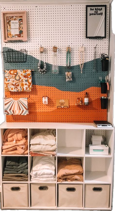 Small business packing station peg board with tee shirts Peg Board Tshirt Display, Boutique Clothing Storage, Home Office Packing Station, Boutique Shipping Station, Small Business Apparel Ideas, Local Store Aesthetic, Small Biz Aesthetic, Small Craft Shop Interior, She Shed Ideas For Small Business