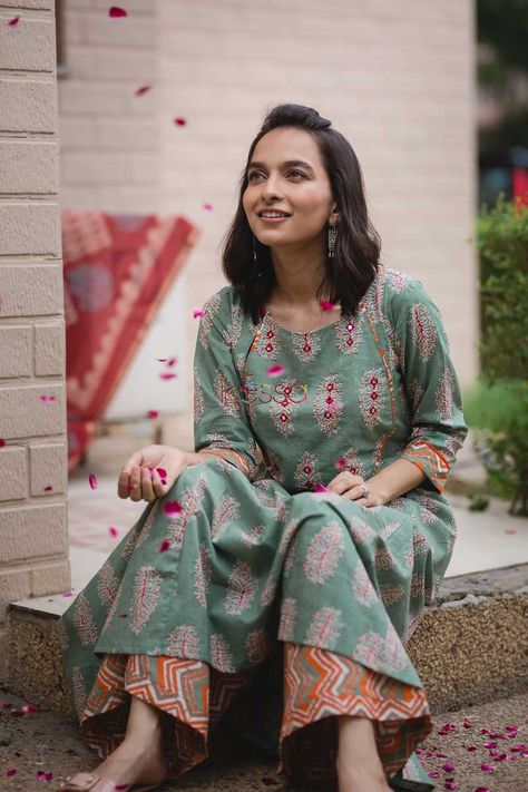 This exquisite set comes with an A-line kurta with ethnic handblock pattern and yoke adorned with multi color piping. The handblock pattern in yoke is decorated with embroidery and mirror work, along with a button enclosure on the neckline. The pants features a vibrant chevron pattern in hues of red, orange, yellow and paradise green. Chevron Pants, Simple Kurti, Cotton Kurtis, Salwar Pattern, Suit Ideas, Kurti Patterns, Simple Kurti Designs, Kurti Neck, Kurti Embroidery Design