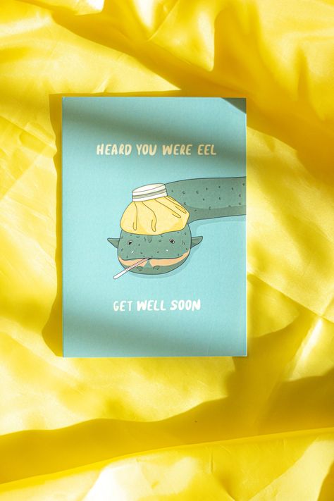 Juu Illustration Eel Get Well Soon Card with Envelope
A cute gift card with an eel illustration on a teal base, reading ''Heard you were eel, Get Well Soon''. Comes with envelope and is blank inside allowing you to write your own message. Part of the Sugar and Style collaboration with Juu Illusration. 

Eel illustration
A6 Size
Blank inside
Includes envelope
Juu Illustration Collaboration Eel Illustration, Knitted Coord, Hexagon Sunglasses, Get Well Soon Card, Dog Birthday Card, Micro Bags, Trending Sunglasses, A6 Size, Skirt Co Ord