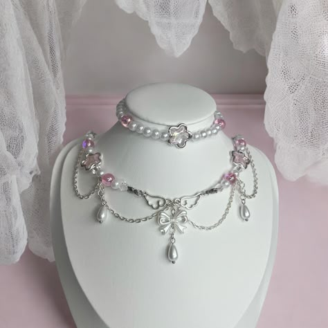 A Cute elegant Royal coquettecore style necklace with pink elements,  includes a bow held up by angel wings as its cenetral charm, and pink and white pearls and glass beads. This necklace was handmade and designed by myself ˏ˚ ༘♡ ⋆｡˚ This necklace will serve as a perfect gift for a freind. Or even better, a perfect gift for you! Your order wil include a clear ziplock storage bag for your necklace and instructions on how to care for your new jewellery. ˏˋo Includes: ✩Necklace  ✩Bracelet The defau Necklace Elegant, Necklace White, Pearl Pink, Esty Shop.com Jewellery, Bracelets With Charms, Croquette Jewelry, Princesscore Handmade Necklace For Gift, Handmade Princesscore Necklace For Gift, Coquette Necklace