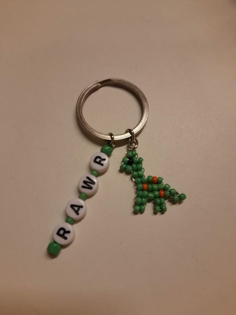 Jewelry With Seed Beads, Things To Make Out Of Seed Beads, Seed Bead Letter Bracelet, Beaded Dinosaur Tutorial, Dino Bead Pattern, Beaded Bracelets Pony Beads, Seed Bead Dinosaur, Green Keychain Aesthetic, Dinosaur Keychain Diy