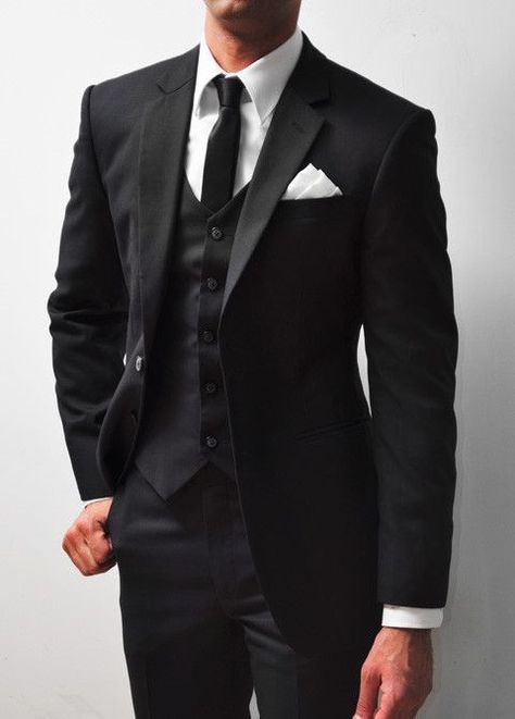 A tuxedo, often referred to as a "tux" in informal contexts, is a formal evening suit distinguished primarily by satin or grosgrain facings on the jacket's lapels and buttons, and a similar stripe along the outseam of the trousers. Traditionally black or midnight blue, the tuxedo is worn with a formal shirt, a bow tie, and patent leather shoes. It is the standard attire for events described as black-tie and is frequently chosen for elegant events, weddings, and sophisticated soirées. Tailored Wedding Suit, Groom Attire Black, Wedding Suits Men Black, Groom Suit Black, Wedding Tux, Groom Wedding Attire, Black Suit Men, Black Suit Wedding, Wedding Suits Groom