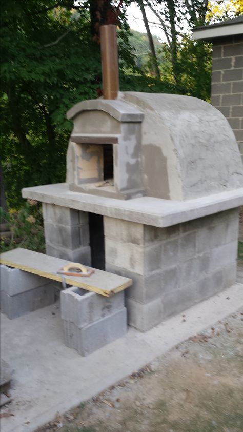 outdoor wood fired pizza oven completed  for less than $400 from scratch. His Italian  ancestral skills came out.   he laid cinder blocks and poured the concrete top leaving an opening for an ash grate.  He used heavy duty Styrofoam  to form the dome. fire brick was used for the base and over the dome shape. wood wedges were used between the brick on top and concrete mix dobbed in all the open spaces. He used a thinner mix to spread over the brick .   chimney was made from a ceramic drain pipe Homemade Pizza Oven, Pizza Oven Plans, Pizza Oven Outdoor Diy, Backyard Pizza Oven, Build A Pizza Oven, Pergola Outdoor Living, Fire Pit Pizza, Oven Diy, Diy Pizza Oven