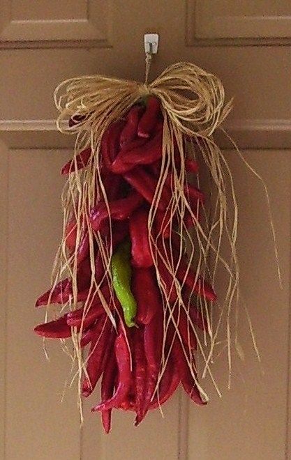 Chili Pepper Ristra: Braid jute poking stems of chilies (I used Anaheim/Hatch chilies from my garden) into each strand as you go and finish with a raffia bow.  Here is a nice demo of how to make one:  https://youtu.be/iSBNMj334pc Pepper Wreath Diy, Chili Ristas, Dried Peppers Decoration, Dried Chillies Hanging, Dried Chili Peppers Decoration, Chili Pepper Decor, Kitchen Wreaths, Backyard Farmhouse, Chili Pepper Jewelry