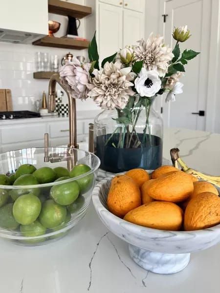 Kitchen hosting essentials with a marble fruit bowl, marble cake stand, plastic clear serving bowl, dipped vase for faux florals and other kitchen decor. #LTKSeasonal #LTKstyletip #LTKhome Modern Fruit Bowl Display, Styling Kitchen Counters, Fruit Basket Ideas, Modern Fruit Bowl, Small Kitchen Island Ideas, Peninsula Kitchen, Fruit Bowl Display, Marble Cake Stand, Tiered Fruit Basket