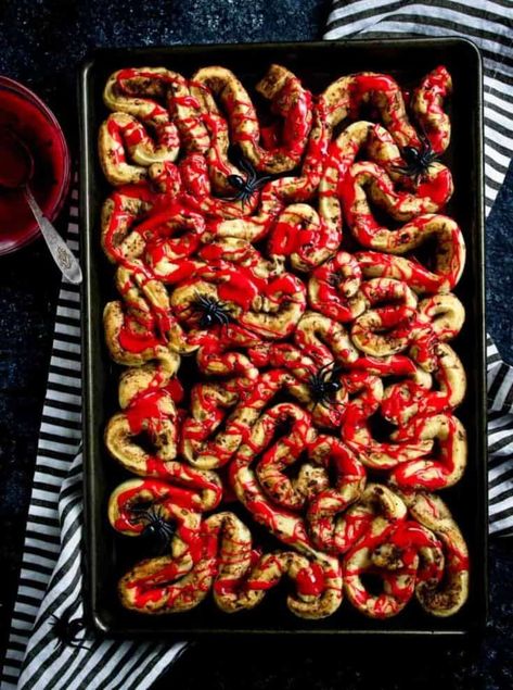 These cinnamon rolls are a gory yet delicious breakfast treat. Using store-bought cinnamon rolls, the dough is unraveled and shaped to resemble intestines. After baking, they're drizzled with a blood-red frosting made from powdered sugar and gel food coloring, creating a creepy effect. These rolls can also be made with green frosting to mimic zombie brains. Easy Halloween Breakfast, Breakfast Cinnamon, Easy Halloween Party Food, Halloween Treats To Make, Creepy Halloween Food, Halloween Food Dinner, Halloween Breakfast, Halloween Food Appetizers, Halloween Foods