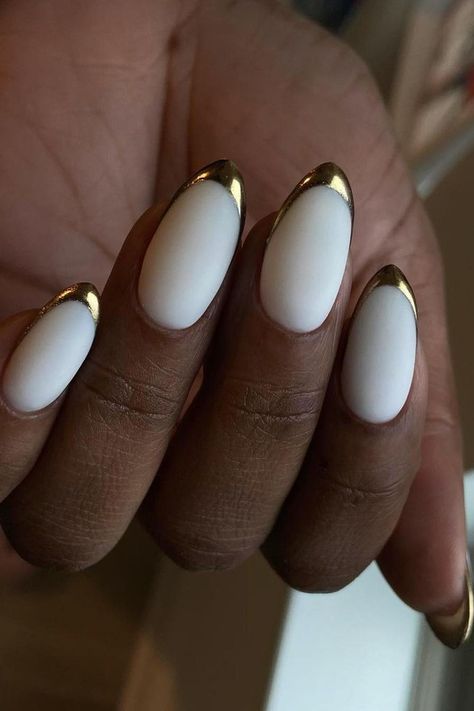 These almond-shaped nails are the epitome of sophistication. A pristine white base is elegantly complemented by a striking metallic gold French tip, adding a touch of luxury and glamour to the design. Perfect for a classy, upscale event or a chic everyday look. Simply gorgeous!✨  // Photo Credit: Instagram @nails.rehab Nail Ideas Elegant Classy, White Gold Tip Nails, Nail Designs With Metallic Lines, White Nails Silver Tips, Nails Gold Tips, Gold Trim Nails, Champagne French Tip Nails, Gold Tip Acrylic Nails, White Nails With Gold Tips