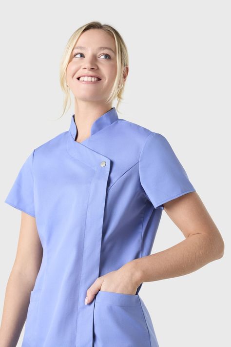 SJ Women's Feature Press Stud Tunic, Pacific Features      Fabric composition: 65% Polyester, 35% Cotton    Crease resistant    Concealed zip fastening    Semi fitted with princess panel styling    Two front upright patch pockets    We recommend washing this garment at 60°    Easy care garment, requiring minimal ironing      Update your healthcare uniform with our Pacific press stud tunic. Designed with a safety focus, the smooth press stud fastening prevents scratching, catching and cannot come Nurses Uniform Modern, Medical Uniforms Woman, Scrubs Fashion, Medical Scrubs Fashion, Housekeeping Uniform, Modern Uniform, Healthcare Uniforms, Stylish Scrubs, Medical Scrubs Outfit