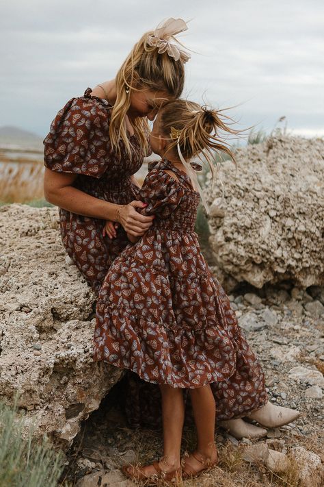 Let your little one flutter into fall with the Mini Daydreamer Dress in Monarch! This brown butterfly print chiffon dress features a sweet square neckline, a smocked bodice for a comfy fit, and a midi-length skirt for endless autumn adventures. Plus, there’s a matching dress for mom—perfect for twinning on those crisp fall days! Dresses For Fall Family Pictures, Brooke Schultz Photography, Fall Picture Dresses For Women, Mom And Child Aesthetic, Family Photo Outfits Boho, Mauve Family Photo Outfits, Mom And Daughter Fall Photoshoot, Fall Family Photos Burgundy, Fall Western Family Photos