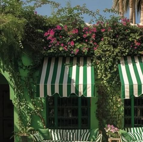 Ann Dennis on Instagram: "Loving greens today…the many shades blend beautifully in this exterior ….the house color, stripe awning, furniture and pillows. I doubt I would have the pool tiles designed in only green, but it works  and is very attractive. Green is such a versatile color and the designer has been very creative in the design.it is stunning with colorful foliage  and flowers. 🌿💚🤍💚🤍🌿 @babtistebohu" Striped Cafe Awning, Awning Furniture, Stripe Awning, Hamptons Design, Outdoor Window Awnings, Striped Awning, Pool Tile Designs, Pool Tiles, Striped Wedding