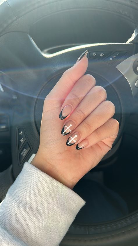 Almond shaped, black french-tip, hard gel nails. Two white accent crosses on the two middle fingers. Hand is in front of a black steering wheel. 50 Cent Nails, Nail Ideas Country Concert, Almond Nails With Cross, Black And White Criss Cross French Tip Nails, Black French Tip Nails Square With Cross, Medium Acrylic Nails With Cross, Cross Gel Nails, Black French Tip Nails With Cross Gem, Black French Tip White Outline