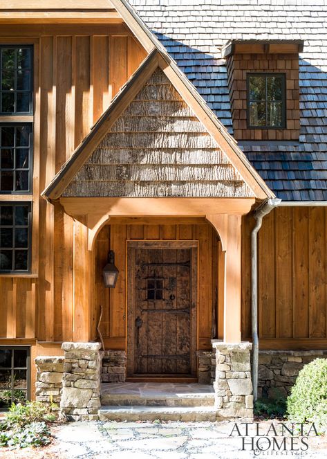 A cedar-shake roof, cypress board-and-batten siding and stacked stones make this home—designed by architect Greg Busch and interior designer Meridy King—look in harmony with the wooded landscape. Board And Batten Siding Stained, Cypress Board And Batten Siding, Stained Board And Batten Exterior, Cedar Exterior House, Board And Batten Cabin, Siding Board And Batten, Cypress House, Cedar Shingle Siding, Exterior House Siding