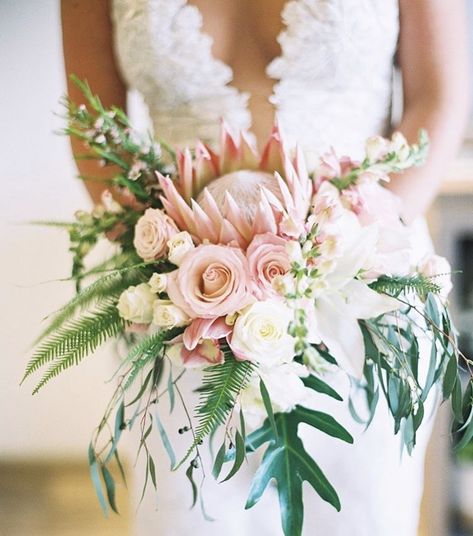 King protea, ranunculus, roses, snap dragons, lillys, palms, tropical greens ties off this beauty for the bashing bride. Protea Wedding Bouquet, King Protea Bouquet, Beach Wedding Table Settings, Tropical Bridal Bouquet, Snap Dragons, Purple Flower Bouquet, Protea Wedding, Beach Wedding Tables, Ranunculus Bouquet