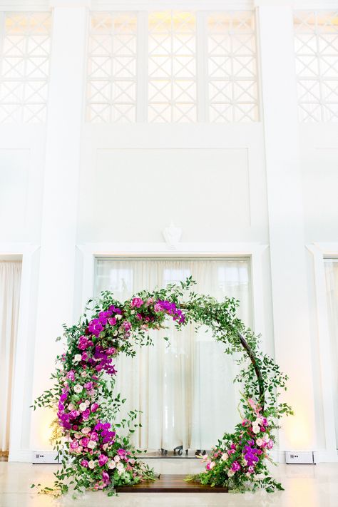 Indoor Downtown Tampa Wedding Ceremony at Tampa Wedding Venue The Vault | Bright Colorful Florida Wedding Ceremony Floral Circle Moon Round Arch with Pink Roses and Purple Orchids and Greenery Round Floral Arch Backdrop, Purple Circle Backdrop, Round Flower Arch Wedding, Floral Wedding Circle Arch, Wisteria Circle Arch, Floral Arch Wedding Indoor, Colorful Flower Arch, Orchid Arch Wedding, Circle Arch With Flowers