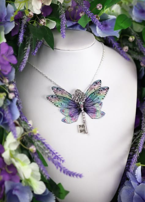 A must-have for all fairies! A unique and truly beautiful rainbow sparkle fairy wing cicada pendant. This necklace is embellished with silver sparkle, gems and a silver key charm. The wings measure approximately 9.5cm across. This delicate array of fairy wings is really rather lovely. It is perfect for all fairy lovers - whether to be worn as part of a costume, or simply as a pendant for everyday wear. It is super light weight, and the wings are slightly flexible to touch. These wings are far more durable than their glassy appearance might suggest! Please note that the wings may grow cloudy over time when exposed to sunlight, heat, perspiration and makeup. The wings should also avoid contact with water. Please store carefully when not wearing, away from direct sunlight. The chain measures Fairycore Jewelry, Fairy Pendant, Fairy Accessories, Pretty Jewelry Necklaces, Fairy Gifts, Fairy Jewelry, Fairy Necklace, Magical Jewelry, Fairy Wings