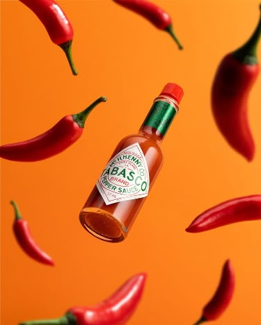 A strongly lit product photography image of an airborne bottle of Tabasco hot sauce surrounded by falling chilli peppers on a gradient backdrop of vibrant orange. #ProductPhotographyInspiration #ProductPhotographyIdeas #ProductPhotographyInspo #ProductPhotography #creativephotography #colorfulproductphotography #vibrantproductphotography #impactfulproductphotography #productphotographystudio #londonproductphotographer #london #photographystyling #foodphotography #colorinspo Tabasco Hot Sauce, Commercial Photography Product, Still Life Product Photography, Creative Advertising Photography, Product Photography Studio, Ad Photography, Chilli Peppers, Brand Photography Inspiration, Product Photography Ideas