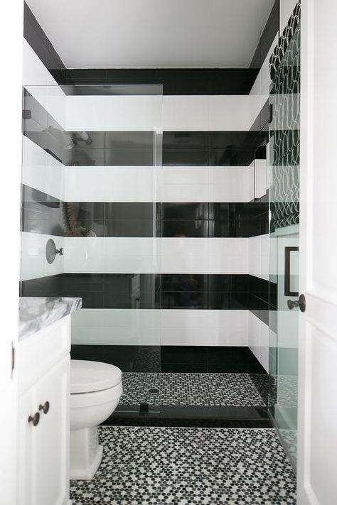 Black and white striped shower surround tiles are fitted with an oil rubbed bronze shower kit fixed behind a glass partition and beautifully complemented with black and white mosaic shower floor tiles which continue out into the bathroom to frame a white washstand. Toilet Tiles Design, Black Tile Bathrooms, Black And White Tiles Bathroom, White Tile Shower, Black White Bathrooms, Bathroom Showers, Bathroom White, White Bathroom Tiles, Bathroom Floors