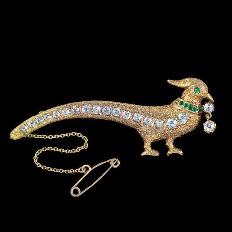 A wonderful antique Edwardian pheasant brooch lined with seventeen sparkling old mine-cut diamonds that graduate from the head all the way down his long tail feathers. They have SI 1/2 clarity – H/I colour and range from 0.06 – 0.20ct (approx. 2ct total).] The head of the bird is also set with an emerald eye, a collar of glistening emerald-green pastes and a double diamond dropper hanging from his beak. It's modelled in solid 18ct gold with feather texturing etched across the front. It's a ... Brooch Diamond, Feather Texture, Emerald Eyes, Double Diamond, Tail Feathers, Antique Brooches, Gold Jewellery Design Necklaces, Cushion Cut Diamonds, Beautiful Doors