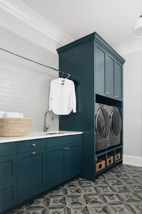 A drying rod is fixed in front of silver backsplash tiles fixed above peacock blue cabinets donning square nickel knobs and a white quartz countertop. Silver Backsplash, Luxury Laundry Room, Black And White Backsplash, Teal Cabinets, Luxury Laundry, Transitional Laundry Room, Laundry Room Countertop, Grey Laundry Rooms, Off White Cabinets