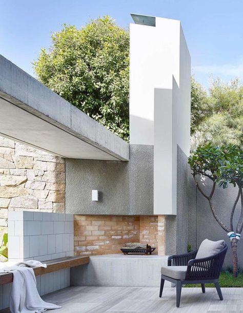 A sculptural concrete chimney not only directs smoke from the fire pit, but provides shade to this pool-side outdoor living space | Photography: Scott Burrows