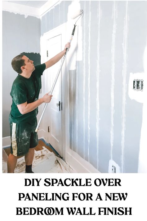 Man applying spackle to a paneled wall in a bedroom. Updating Wall Paneling, Filling Paneling Grooves, How To Cover Up Paneling Walls, Update Wall Paneling, Cover Wood Paneling Ideas, Basement Wall Paneling Ideas, Ideas For Wood Paneling Walls, Cover Up Paneling Walls, Covering Wall Paneling Ideas