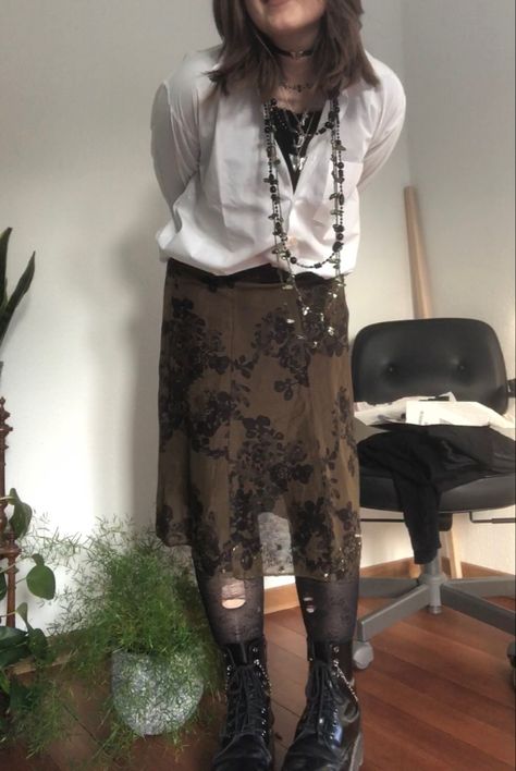 A mid-size person/girl wearing a closed wide white button up with a black ripped tights longsleeve under it, a dark green flower midi skirt, rose patterned stockings,  black platform dr. Martens and multiple crystal rings and bracelets. 	The person is also wearing multiple silver necklaces; one in form of a moon, a butterfly, and one in form of a fairy, a long black and green bead necklace and a green buttery choker. Antique Grunge Outfits, Descendants Redesign, Rose Stockings, Fit Aesthetic Outfit, Rock Aesthetic Outfits, Punk Aesthetic Outfit, Pirate Lady, Antique Grunge, Necklaces Butterfly