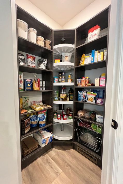 This photograph is looking into a walk-in pantry closet that has been upgraded to have a custom organization system installed in our vintage rio finish. This pantry design includes adjustable shelves, pull-out wire baskets of two sizes. It also has a Lazy Susan and toe kicks that push a floor vent forward so that the air to the room isn't impeded by the system. Mini Walk In Pantry Ideas, Large Corner Pantry Walk In, Walk In Pantry Wire Shelving, Kitchen Lazy Susan Ideas Corner Pantry, Corner Pantry Built In, Angled Pantry Ideas, Lazy Susan Pantry Organization, Triangle Pantry Organization, Walk In Food Pantry Ideas