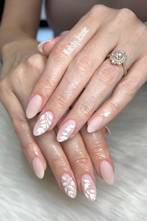 Discover More Nail Ideas: Embrace Serene Chicness with Matte Pink Oval Nails and Enchanting White Leaf Accents. Click Here to Get Inspired! // Photo Credit: Instagram @nailsbyjennie92 Wedding Guest Nails Almond Shape, Wedding Nail Inspo For Bride Almond, Engagement Nails Short Almond, Bridal Nails Wedding Elegant Almond Shape, Wedding Nails For Bride Flowers, Wedding Nails Leaves, Bridal Floral Nails, Elegant Wedding Nails For Bride Almond, Almond Nails Designs Wedding