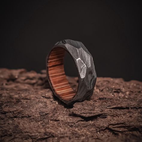 The Hams, features a bold and intricate pattern that symbolizes strength and durability. The rich hardwood sleeve adds a touch of natural elegance, offering a unique contrast to the rustic damascus exterior. Perfect for those seeking a distinctive, handcrafted wedding band or statement piece that blends craftsmanship with timeless design. Each ring is meticulously made to order, ensuring no two are alike. A truly one-of-a-kind piece for the modern man. Specs: Band Width: 8 mm Band Thickness: 1.8 Rings Engagement For Men, Engagement For Men, Whiskey Barrel Ring, Wedding Ring Minimalist, Fiance Ring, Rustic Wood Box, Damascus Ring, Ring For Man, Damascus Steel Ring