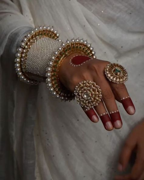 Surabhi didwania on Instagram: "Elevate your style with our exquisite hand stack, a timeless tribute to cultural opulence. Adorn your wrist with our uniquely shaped, intricately detailed silver bangles & kada, handcrafted with precision by our master craftsmen. Featuring the royal pearls design on kada and exquisite meenakari on gold-toned pacheli, each piece looks absolutely adorable. Elevate your elegance with these timeless treasures. Each piece exudes elegance and sophistication, ensuring you make a statement wherever you go. Let the timeless beauty of silver capture every eye.  Adrta : S16682310 Abheri : S17739964 Oversize ring with rubies : S9362261 Floral Ring : S16359340  Shop now on www.mymotifs.com We deliver worldwide 🌍🌎✈️  #finejewellery #gemstones #silverjewellery #indianjew Pacheli Bangle Gold, Hand Stack, Hand Chain Jewelry, Diy Fabric Jewellery, Fabric Jewellery, Floral Ring, Pearl Design, Fancy Jewellery, Hand Chain