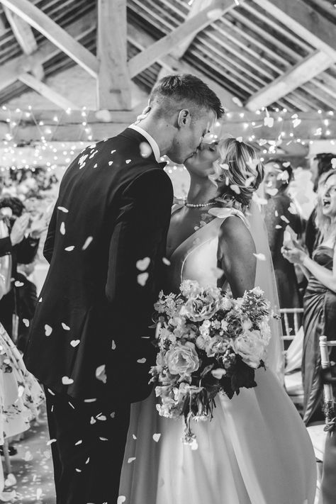 Groom in black tuxedo and bride in wedding dress with bow details on the sleeves kissing the groom during confetti exit | confetti moment | wedding photo idea | black and white wedding photography | Jessica Hopwood Photography Confetti Photo Wedding, Confetti Wedding Exit, Bride In Wedding Dress, Wedding Dress With Bow, Wedding Photo Idea, Black And White Wedding Photography, White Wedding Photography, Confetti Photos, Wedding Send Off