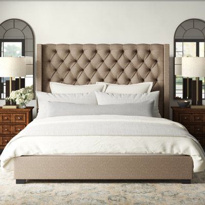 Bring streamlined style to your bedroom or guest room with this upholstered low-profile bed. It’s made of engineered wood with foam padding and 100% polyester upholstery in a neutral brown shade; a tall wingback design and button-tufted detail give this piece a classic, tailored look. This piece comes with slats and center support legs, for added stability; we recommend a 12” thick mattress (sold separately, along with the box spring). This bed completes the look in any traditional or glam setti Tuffed Beds Upholstered, Wayfair Upholstered Bed, Tall Headboard Bedroom Ideas, Brown Upholstered Bed, Tall Bed Frame, Taupe Bedding, Tufted Upholstered Bed, Tall Bed, Bedroom Redo