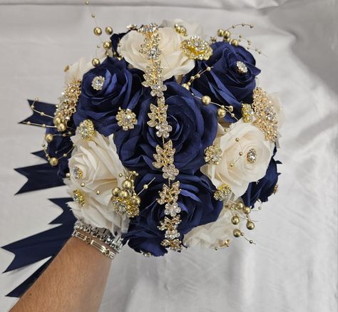 Handmade quinceañera - sweet 16th bouquet with Navy and Champagne roses. Finished off with Gold brooches. Décor can be changed upon request. *This is a made to order bouquet* *Please note brooches can change in style based on availability* Quincenera Dresses Blue And Gold, Quinceanera Navy Blue Decorations, Navy Blue Masquerade Quince, Navy Blue Quince Bouquet, Quince Dark Blue Theme, Quince Blue And Gold, Quince Decorations Blue And Gold, Navy Blue And Gold Quinceanera Ideas, Navy Blue And Gold Sweet 16 Theme