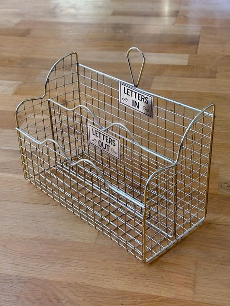 Mid century wire desk organizer with metal "Letters In" & Letters Out" labels. Stands, or has a loop to hang. In great condition. Perfect for a desk, or to hold books, remote controls, etc. Also looks great on the wall with pretties displayed in it. A gold-tone metal, not brass. Dimensions: 10 inches wide x 5 inches deep x 8.5 inches tall (two sections 2 inches wide each) Vintage items will likely show signs of age and use. This is part of their vintage charm. All sales are final, I do not accept any returns, exchanges, or cancellations on vintage items. Merchandise is sold in "As Is" vintage condition. I do my best to illustrate full item details in photos, please review pictures carefully before ordering. All items are safely packaged to ensure that they reach you in perfect condition. P