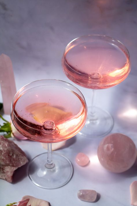 I've got a pretty pink Rose Quartz Cocktail for you that's just going to fill you with the energy of gentle love. It's sweet and floral and refreshing. Raise a glass of this rose-infused gin cocktail with someone you love. Made with homemade rose syrup, this drink can also be made with non-alcoholic gin. #cocktailrecipe #rosecocktail #lovespell #spellcocktail #witchcraft Gin Rose Cocktail, Rose Gin Cocktail Recipe, Rose Vodka Cocktail, Fairy Cocktails, Bday Charcuterie Board, Rose Gin Cocktail, Rose Water Cocktails, Cottagecore Cocktail, Fairycore Birthday