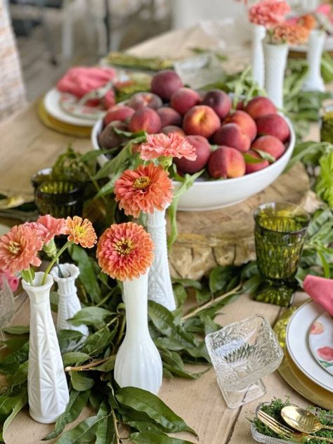 We're in the peak of peach season so it's the perfect time to create a unique tablescape with these beauties. I'm sharing some peach inspired tablescape ideas for summer entertaining with you. Fresh peaches, peach leaves, fresh flowers in orange and peach hues, thrifted plates, and vintage goblets were some of the things I used to create a unique summer table. I also shared a creative way to display your flatware and some tips for finding beautiful items for table decor on a budget. Peach Table Decor, Peach Tablescape, Peach Theme Table Decor, Peach Table Setting, Tablescape With Fruit And Flowers, Vintage Goblets, Summer Tablescapes, Summer Entertaining, Summer Soiree