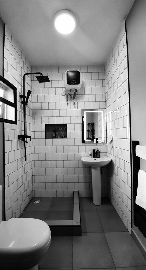 White tiles with black grout, mature black fittings and black towel rail. #Nigeria #Abuja #construction #renovation Toilet Black Tiles, Small Monochrome Bathroom, Black Tile Black Grout Bathroom, Black Wet Room, White Bathroom Tiles With Black Grout, Black Square Tile Bathroom, Bathroom White Tiles Black Grout, White Tiles Black Grout Bathroom, Industrial Toilet Design