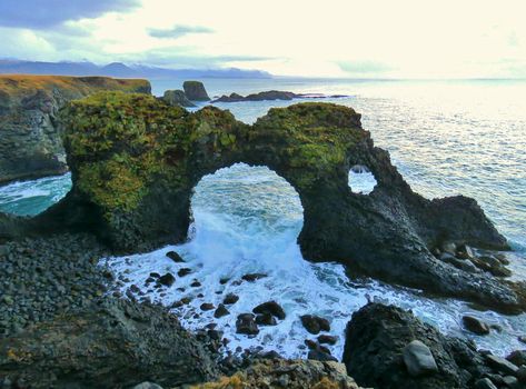 Gatklettur Arch, Iceland.Located near Arnarstapi, at Snæfellsnes Peninsula, West Iceland.  Gatklettur (“Hole cliff”) is a cliff with a circular arch. Rock Arch shows how distinctive wave action has eroded the rocks into arches and beautiful swirled patterns. There is great birdlife around the cliffs and pretty flora surrounding the area. Circular Arch, Rock Arch, Midnight Summer, West Iceland, Snaefellsnes Peninsula, Ocean Rocks, Beach Rocks, Holiday Destinations, Fall 2024