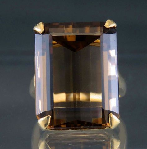 Presented is an eye-catching 14 karat yellow gold and smoky quartz cocktail    ring. This ring dates to around the 1950s and is likely of American make. The    ring is set with a rectangular or emerald-cut smoky quartz, measuring about 22    by 17.5 by 13 millimeters, or about 33.5 carats. Quite a large and impressive    stone, beautifully cut and faceted.      The interior of the band is stamped 14 for 14 karat gold, nitric acid tested    and guaranteed.     The ring is in great condition. The