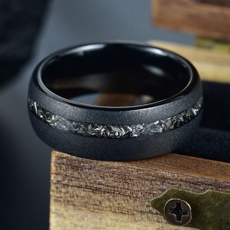 "This black wedding ring features a Bold & Rustic sandblasted finish, tungsten band, with an offset Gibeon meteorite inlay that is OUT OF THIS WORLD! We only use 100% REAL AUTHENTIC meteorite in every ring. The Crushed meteorite are from a larger piece of Gibeon Meteor and is then set for the inlay. Sandblasted black Tungsten Carbide creates a Bold & Rustic Ring! This is sure to catch the eye and have people asking \"What kind of ring is that?!\" Specs: Band Width: 8 mm Band Thickness: Circa 1.8 Meteor Ring, Meteorite Engagement Ring, Mens Wedding Rings Black, Meteorite Wedding Rings, Antler Wedding Band, Mens Wedding Bands Black, Meteorite Wedding Band, Gibeon Meteorite, Guy Gifts