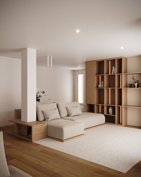 Modern living room with a clean, minimalist aesthetic. 
A beige sectional sofa is placed against a pillar, complemented by a wooden side table. The space features a large wooden bookshelf with decorative items, adding warmth to the neutral tones. The light wood flooring and soft rug create a cozy atmosphere, while recessed lighting highlights the room's simple yet elegant design. Pillar In Living Room, Clean Minimalist Aesthetic, Light Wood Flooring, Sectional Sofa Beige, Beige Sectional, Wooden Bookshelf, Minimalist Sofa, Light Wood Floors, Column Design