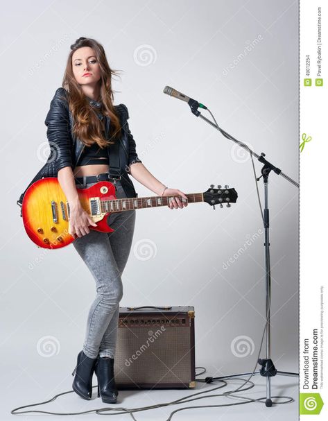 Photo about Young woman standing in front of microphone and holding guitar in her hand. Image of guitar, musical, black - 49012254 Holding A Guitar Pose, Guitar Holding Pose, Holding Guitar Pose Reference, Holding A Guitar Reference, Hand Holding Guitar, Person Holding Guitar Reference, Holding Guitar Reference, Person Holding Guitar, Holding Guitar Pose Drawing